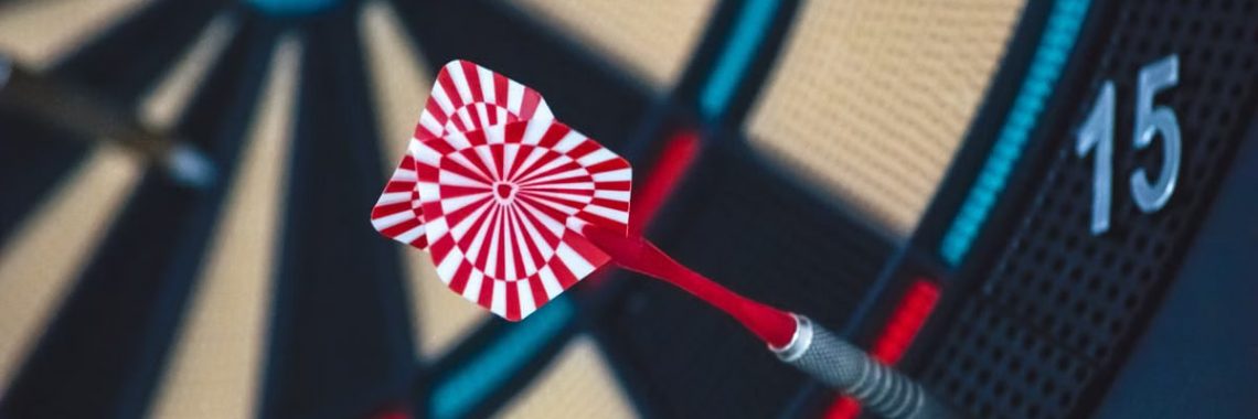A dart striking the bullseye on a dartboard, showcasing precision and accuracy.